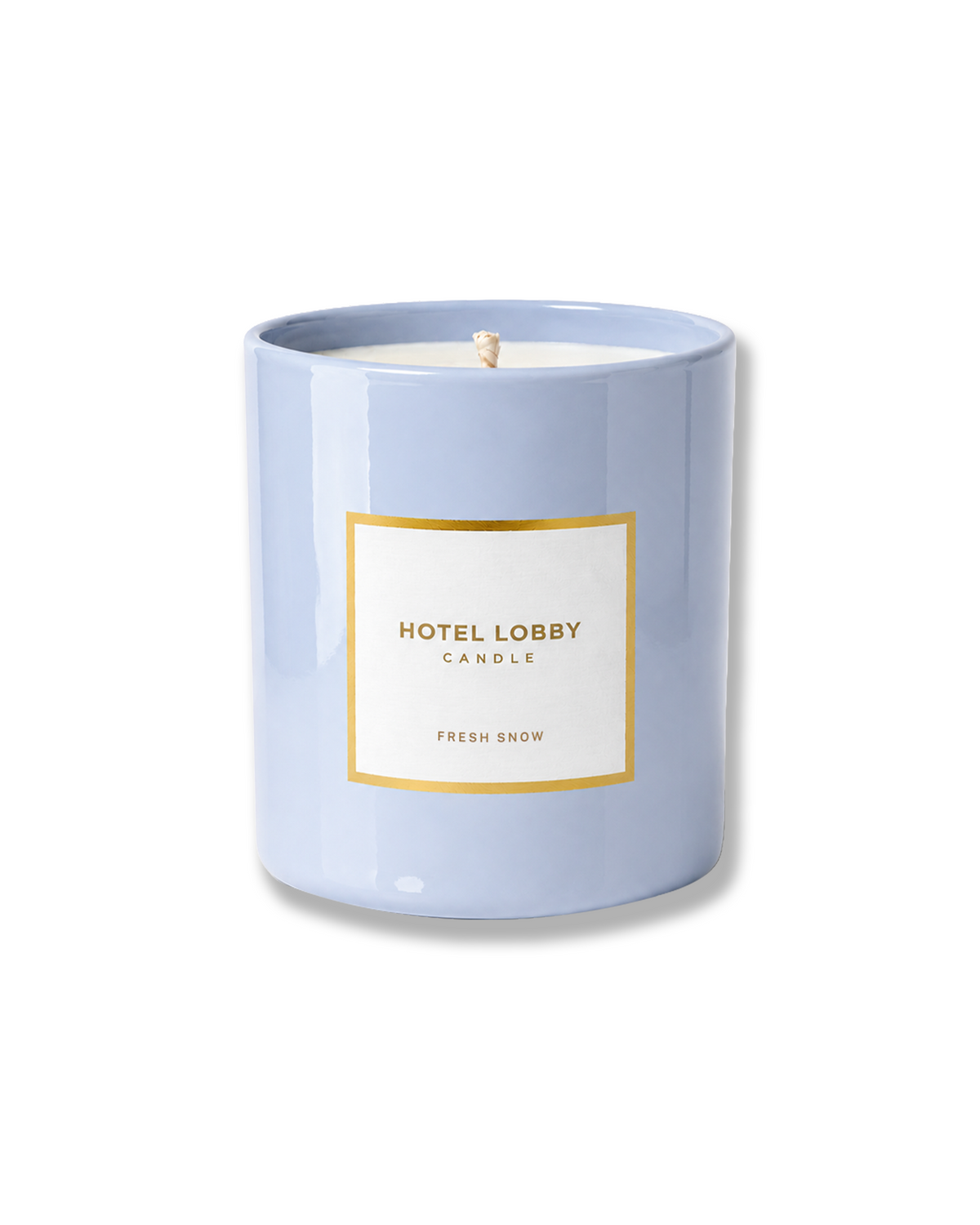 Light blue ceramic candle vessel with white wax, a single wick, and a white label with gold trim featuring the Hotel Lobby Candle Fresh Snow branding.
