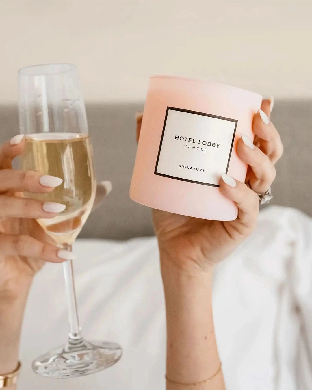 Person holding a pink candle labeled 'Hotel Lobby' and a glass of champagne.