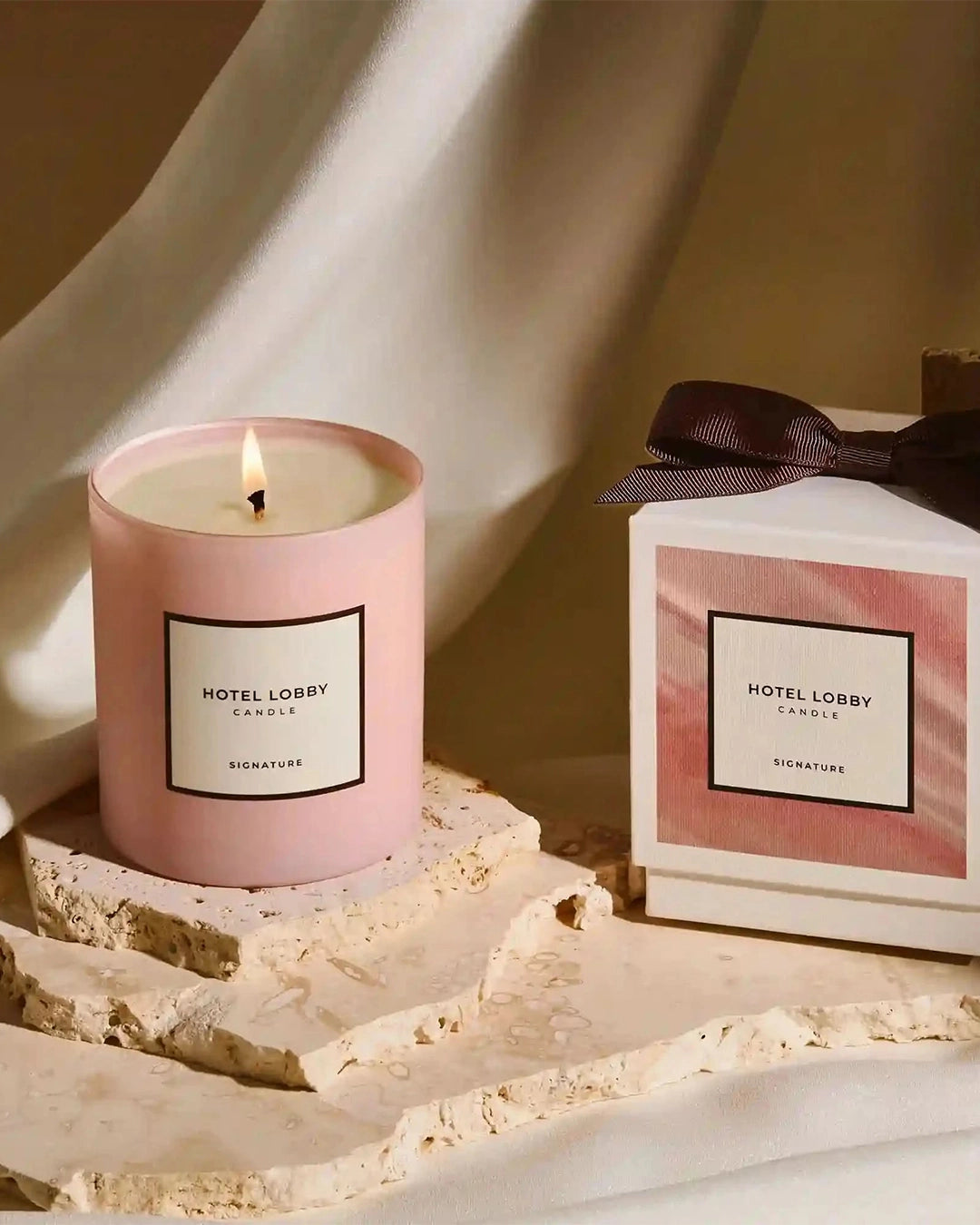 Pink candle and packaging with 'Hotel Lobby' branding on a textured surface.