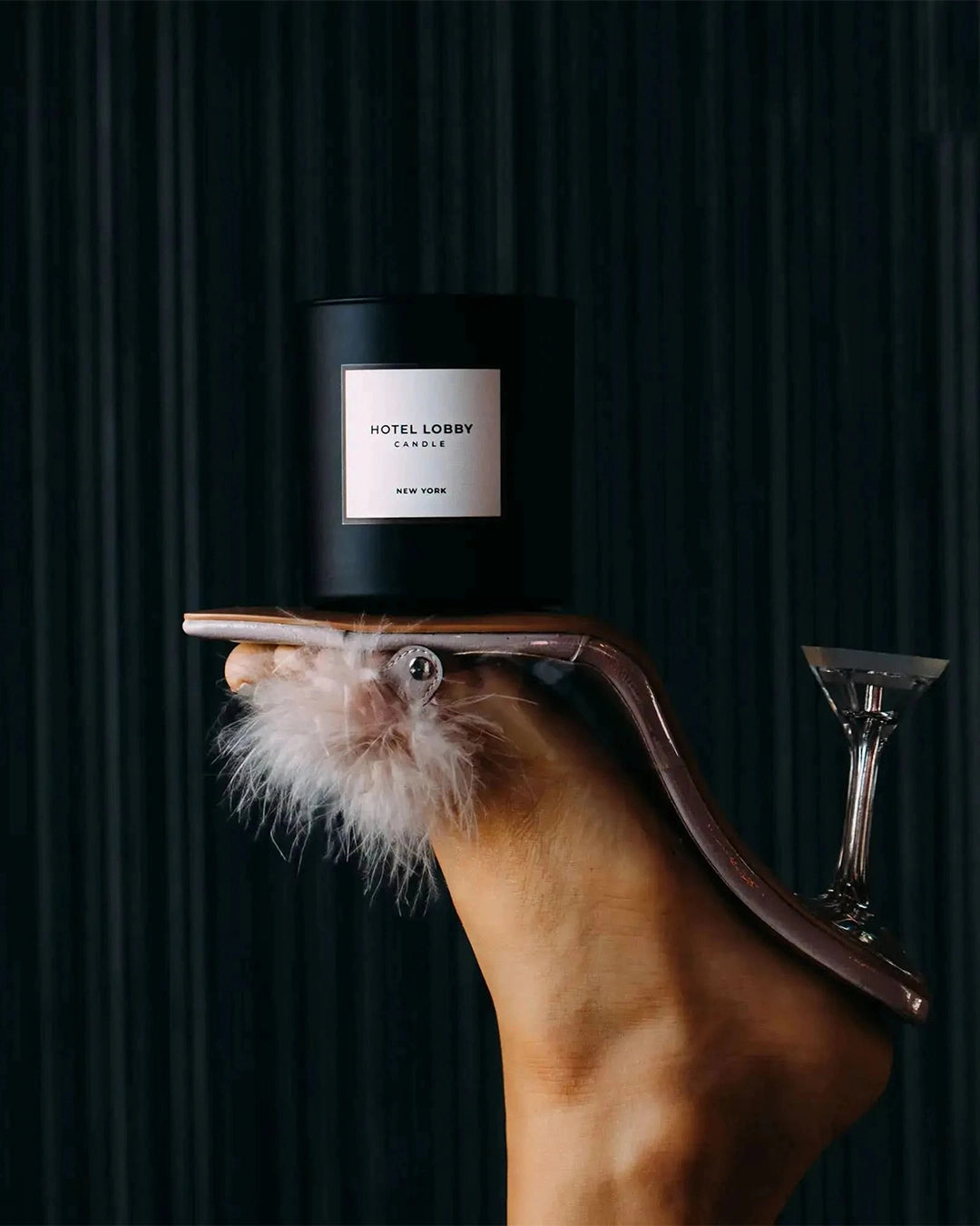 Candle labeled 'Hotel Lobby' on a heeled foot with a dark background