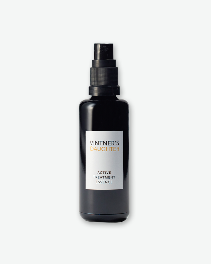 A product shot of a Vintner's Daughter Active Renewal Cleanser bottle, centered against a plain light gray background. The cylindrical bottle is made of deep black glass and is equipped with a matching black pump dispenser. The front features a clean white rectangular label printed with the words "VINTNER'S" in black, "DAUGHTER" in amber, and "ACTIVE RENEWAL CLEANSER" near the bottom.