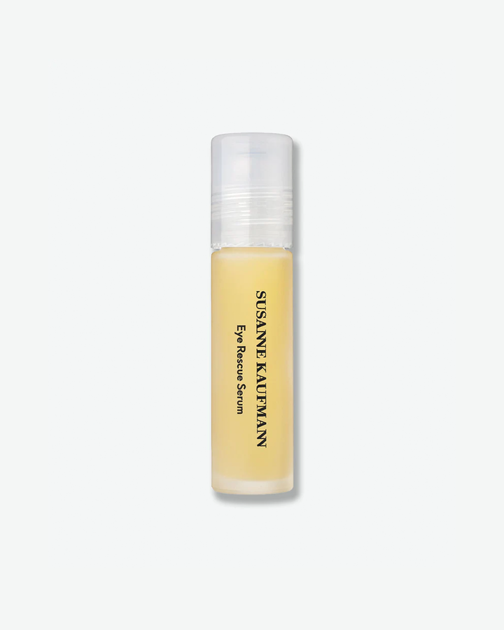 A product shot of a Susanne Kaufmann Eye Rescue Serum rollerball bottle, centered against a plain light gray background. The slender, tall cylindrical bottle is made of frosted glass, revealing a light yellow liquid formula inside. The brand name and product title are printed vertically in black text along the front, and the bottle is capped with a tall, clear plastic cover.