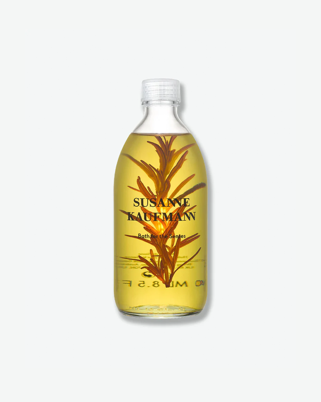 A product shot of a Susanne Kaufmann Bath for the Senses bottle, centered against a plain light gray background. The clear glass bottle is filled with a pale golden-green liquid bath oil that contains a large, intact sprig of rosemary submerged inside. It is sealed with a clear ribbed plastic cap and features the brand name in black typography printed on the front.