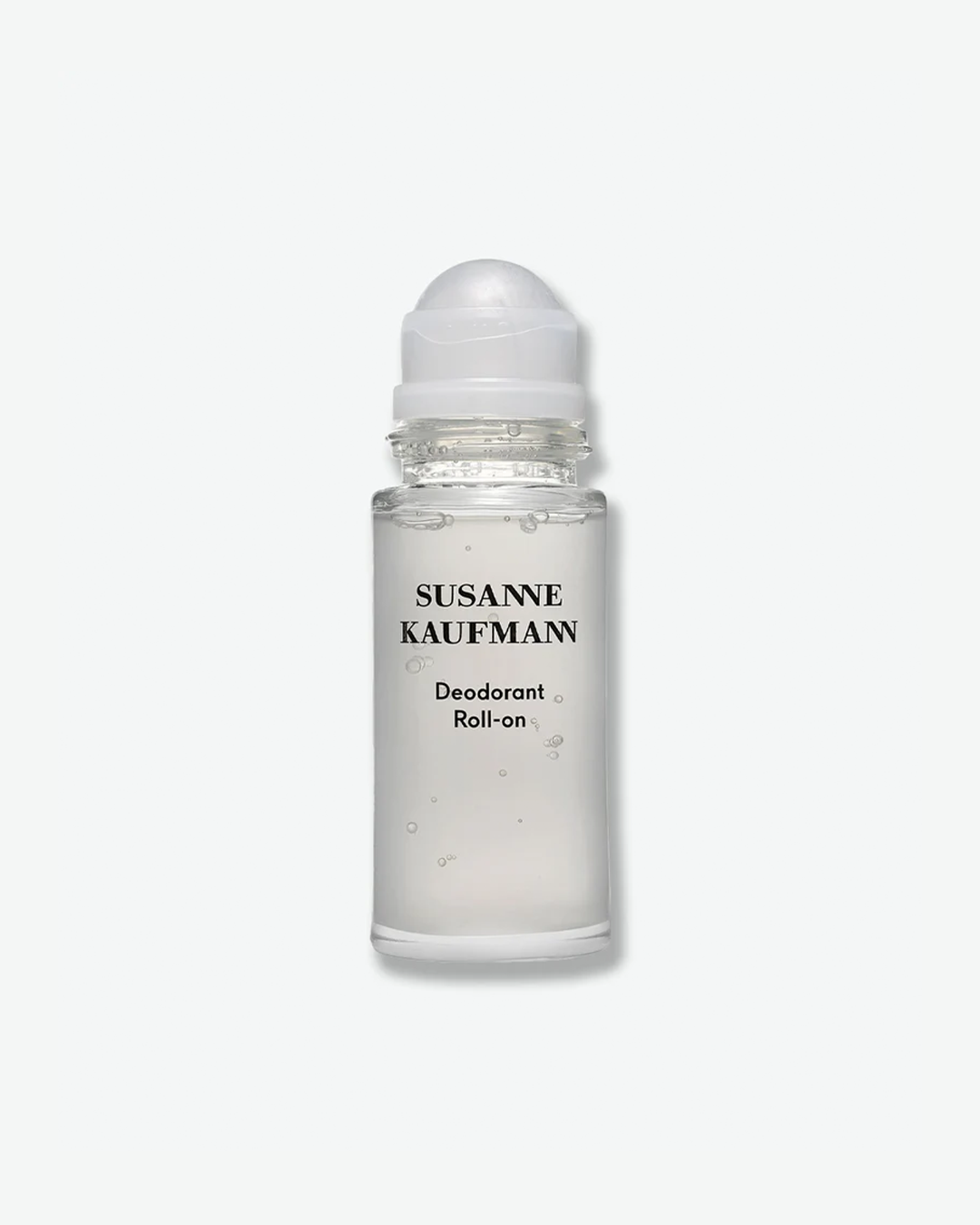 A product shot of a Susanne Kaufmann Deodorant Roll-on, centered against a plain light gray background. The cylindrical clear glass bottle reveals a semi-translucent liquid formula with small, suspended air bubbles. The front displays the brand name in black text above the words "Deodorant Roll-on," and the bottle is topped with a smooth, domed white roller-ball cap.