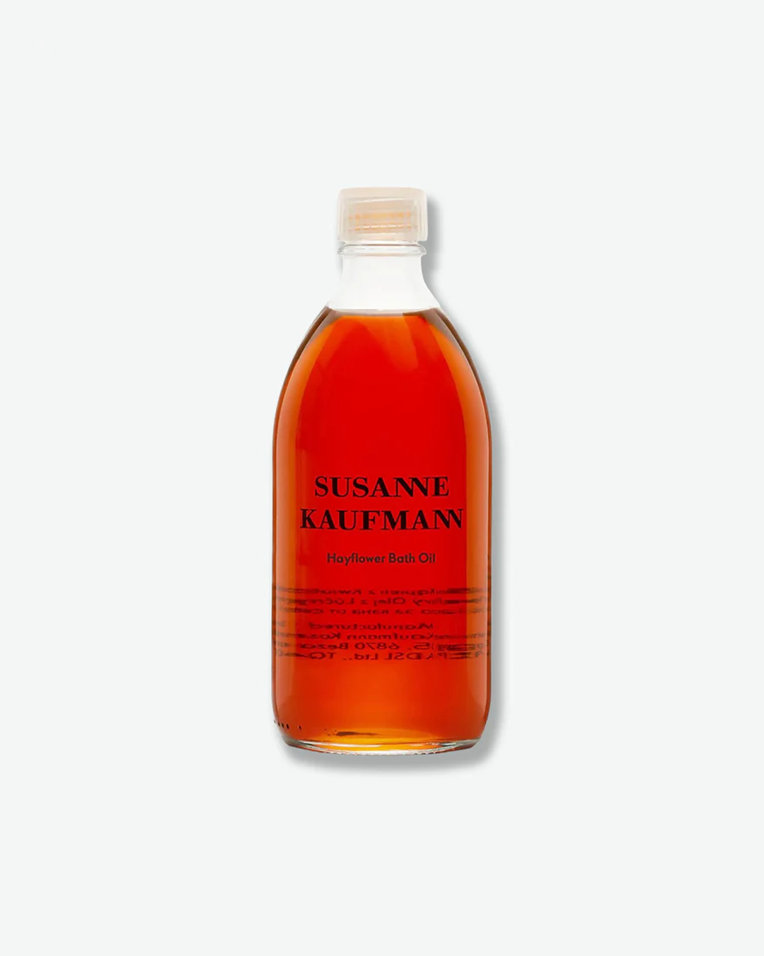 A product shot of a Susanne Kaufmann Hayflower Bath Oil bottle, centered against a plain light gray background. The curved clear glass bottle is filled with a rich, translucent dark amber-red oil liquid. It is fitted with a simple clear plastic screw cap and displays the brand name and product title in clean black typography on the front.