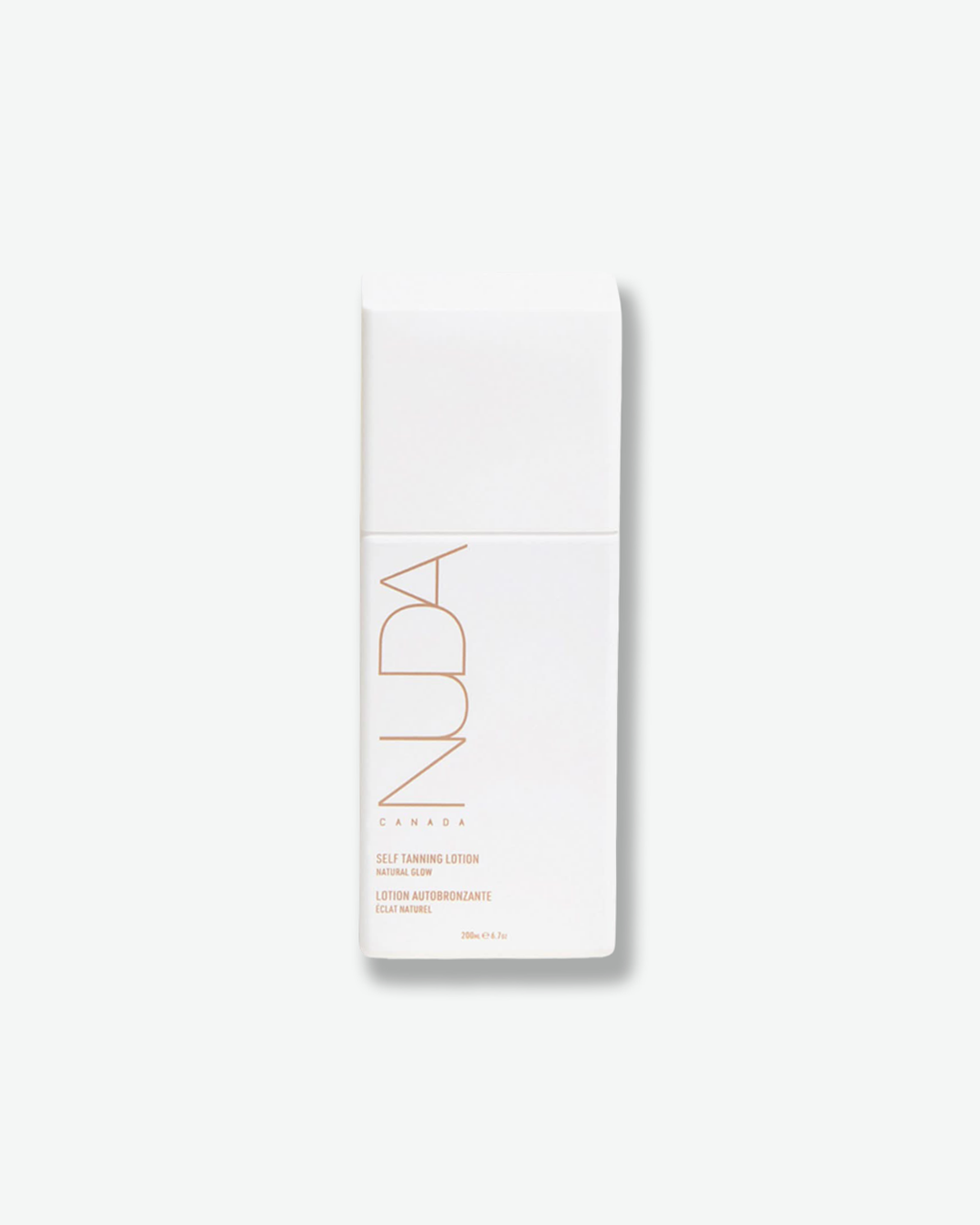 A product shot of a NUDA Self Tanning Lotion container, centered against a plain light gray background. The square, matte white plastic bottle has a flush matching white cap. The front features the brand name "NUDA" printed vertically in a thin, rose-gold outline font above the words "CANADA", "SELF TANNING LOTION NATURAL GLOW", and its French translation, ending with the volume "200ml e 6.7oz".