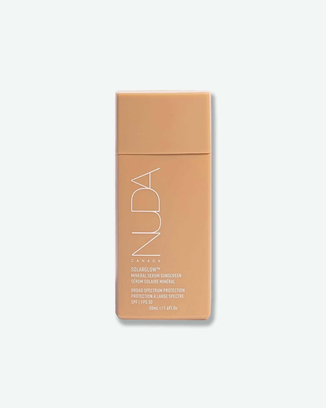 A product shot of a NUDA Solarglow Mineral Serum Sunscreen container, centered against a plain light gray background. The rectangular, matte tan plastic bottle features a flush matching tan cap. The brand name "NUDA" is printed vertically in a thin white outline font on the front, above white text detailing the product name, its French translation, "BROAD SPECTRUM PROTECTION", and "SPF | FPS 30", ending with the volume "50ml e 1.6Fl.Oz".