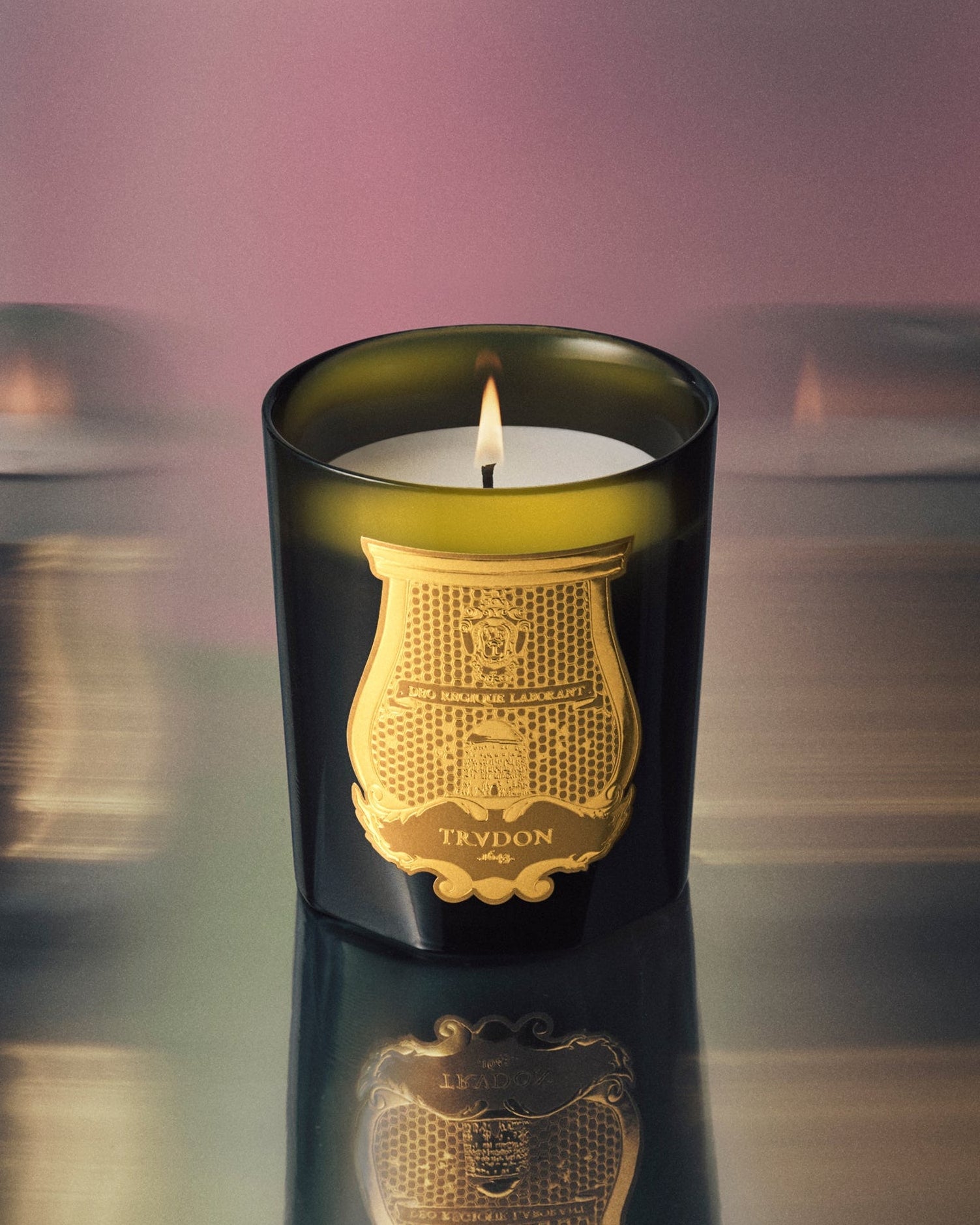 Trudon candle with decorative lid on a reflective surface