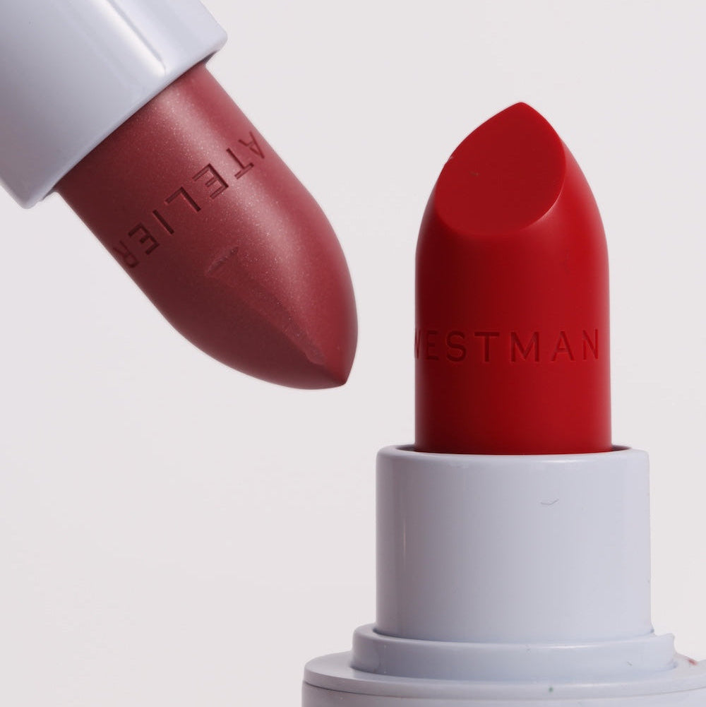 Two Westman lipsticks, one red and one brown, on a white background.