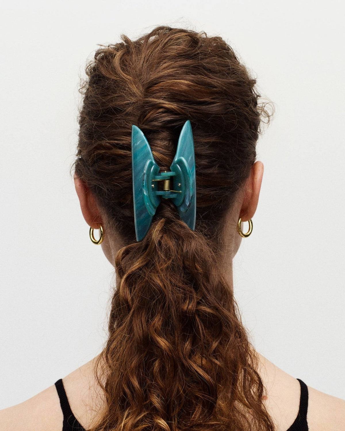Teal hair clip in a person's hair on a white background
