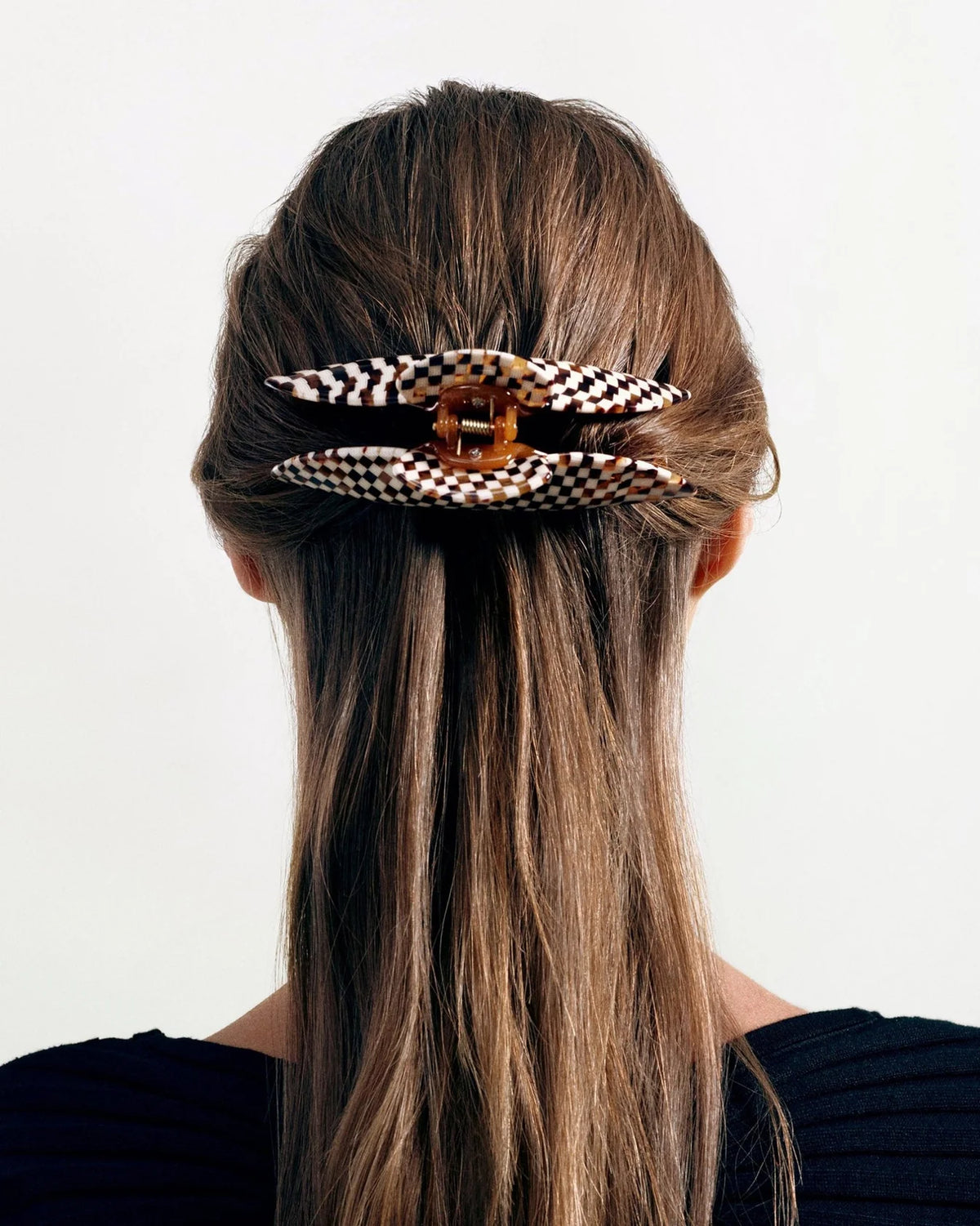 Person with long hair wearing a decorative hair clip on a plain background
